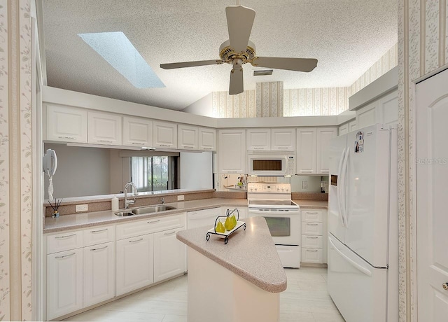 kitchen with wallpapered walls, white appliances, a textured ceiling, and a sink