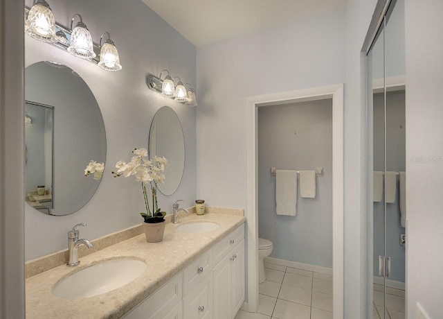 bathroom featuring tile patterned floors, toilet, double vanity, and a sink