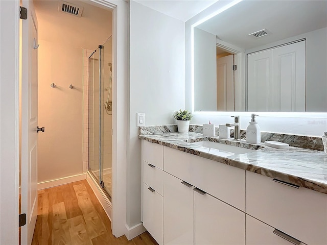 bathroom featuring vanity, hardwood / wood-style floors, and a shower with shower door