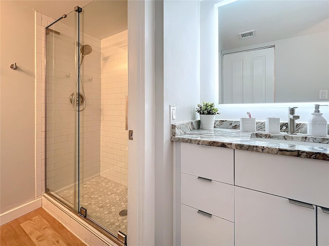 bathroom featuring hardwood / wood-style flooring, vanity, and a shower with shower door