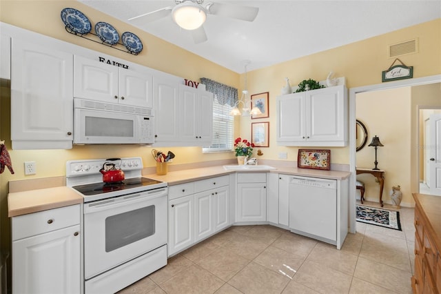 kitchen with sink, white appliances, light tile patterned floors, hanging light fixtures, and white cabinets