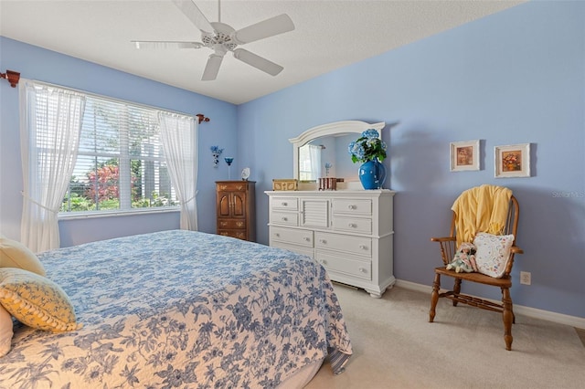 bedroom featuring a textured ceiling, light colored carpet, and ceiling fan