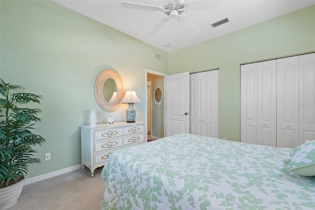 carpeted bedroom with ceiling fan and two closets