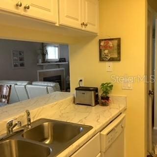 kitchen with light stone countertops, sink, white cabinets, and white dishwasher