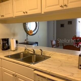 kitchen with light stone countertops, sink, and white cabinets