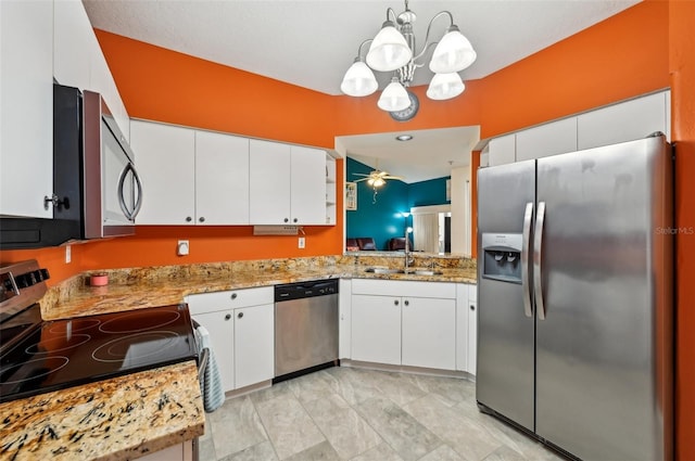 kitchen with sink, white cabinets, hanging light fixtures, light stone counters, and stainless steel appliances