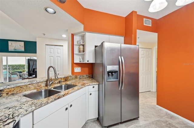 kitchen with white cabinets, sink, stainless steel fridge, and light stone counters