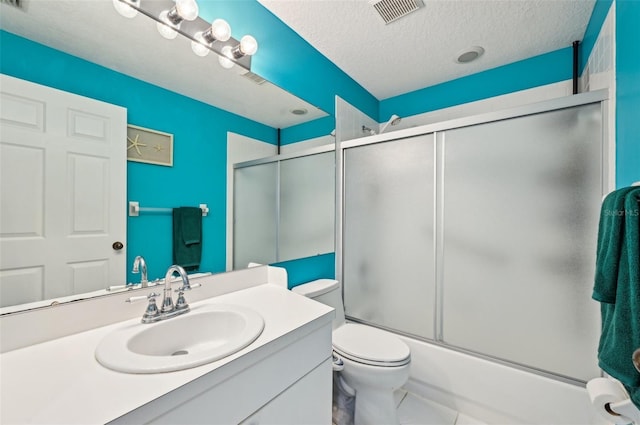 full bathroom featuring shower / bath combination with glass door, tile patterned flooring, vanity, a textured ceiling, and toilet