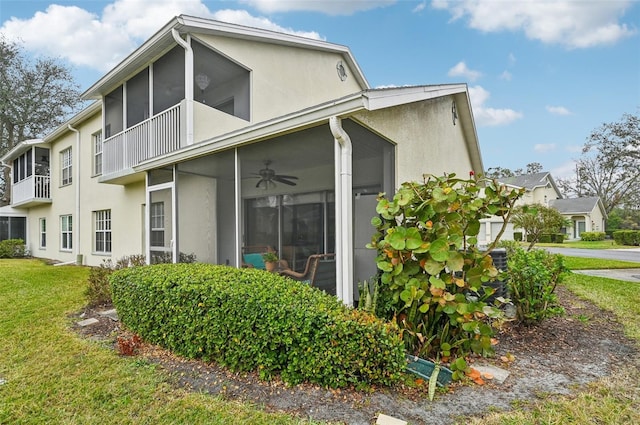 back of house featuring ceiling fan, a balcony, a sunroom, and a lawn