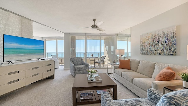 carpeted living room featuring expansive windows, ceiling fan, and a water view