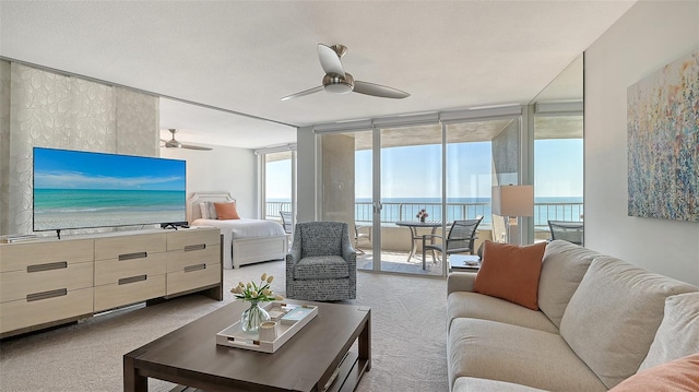 carpeted living room featuring a wall of windows, ceiling fan, and a water view