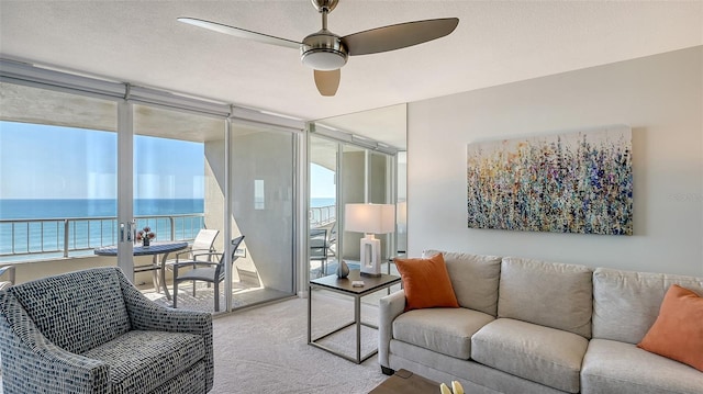 carpeted living room featuring floor to ceiling windows, a water view, a textured ceiling, and ceiling fan