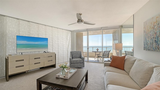 living room with expansive windows, ceiling fan, and carpet flooring