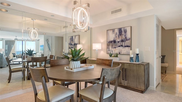 dining area featuring a tray ceiling, light colored carpet, and a chandelier