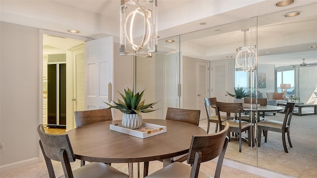 carpeted dining area featuring a tray ceiling and a chandelier