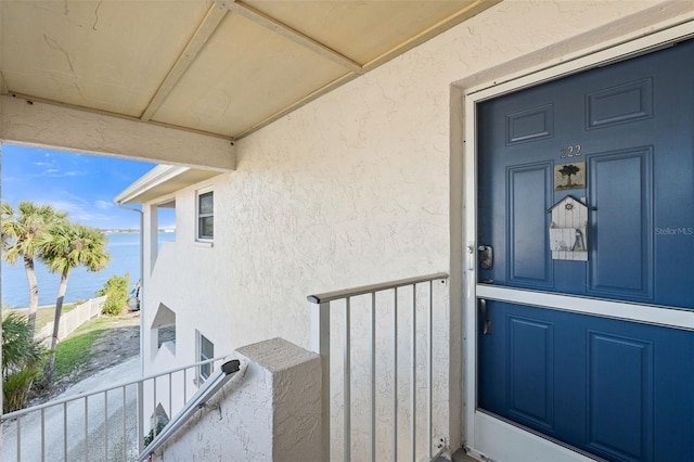 doorway to property with a balcony and a water view