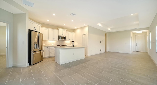 kitchen with sink, white cabinetry, tasteful backsplash, appliances with stainless steel finishes, and a kitchen island with sink