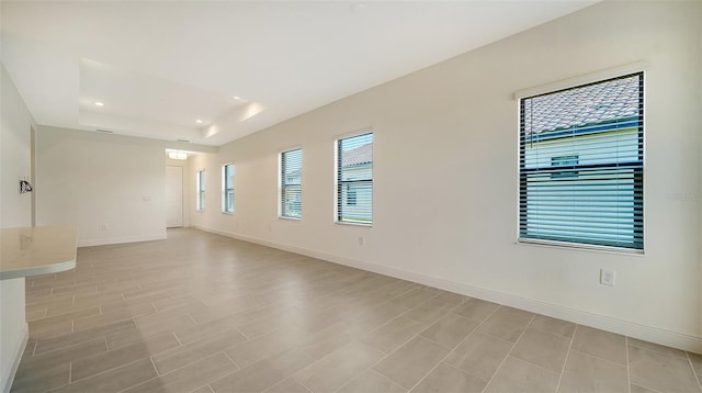 spare room with a raised ceiling and light hardwood / wood-style flooring