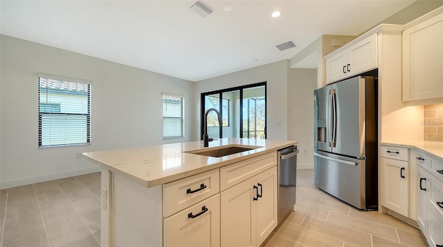 kitchen with an island with sink, stainless steel appliances, sink, and white cabinets