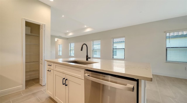 kitchen featuring sink, dishwasher, a kitchen island with sink, white cabinetry, and light stone countertops