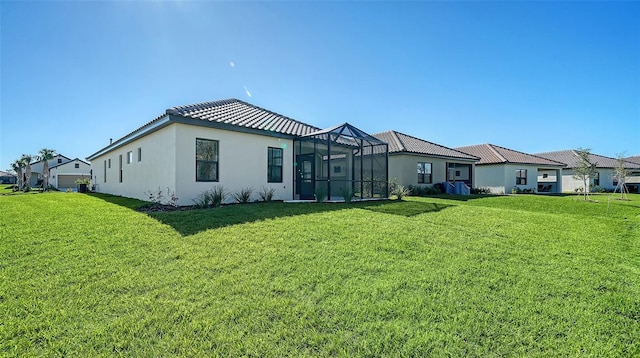 rear view of property with a lanai and a lawn