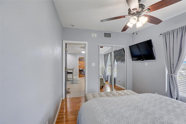 bedroom featuring a ceiling fan, visible vents, baseboards, and wood finished floors