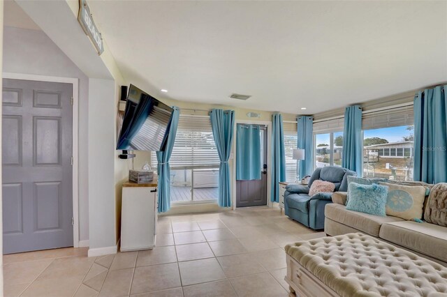 living room with light tile patterned floors, baseboards, visible vents, and a wealth of natural light