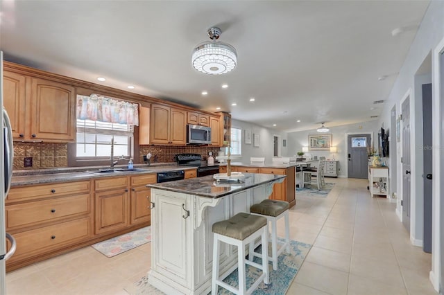 kitchen with black appliances, tasteful backsplash, a kitchen breakfast bar, and a center island