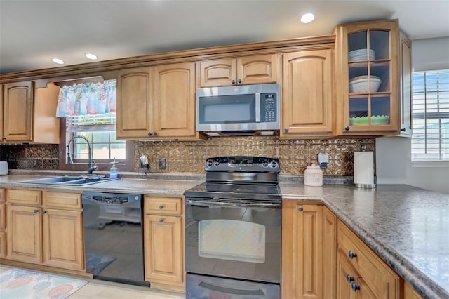 kitchen featuring recessed lighting, a sink, backsplash, black appliances, and glass insert cabinets