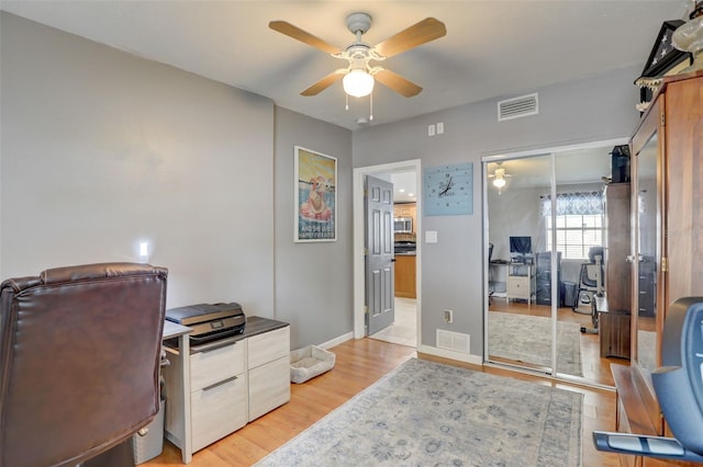 office space with baseboards, light wood-style flooring, visible vents, and a ceiling fan