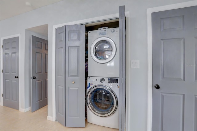 laundry area featuring stacked washing maching and dryer, laundry area, and light tile patterned flooring