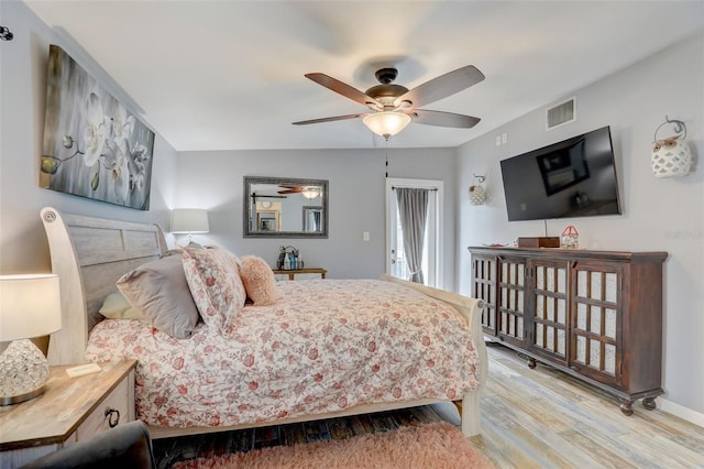 bedroom with ceiling fan, wood finished floors, visible vents, and baseboards