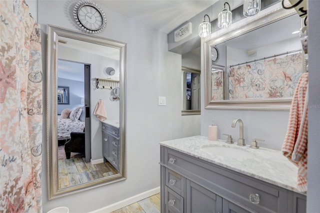 ensuite bathroom with wood finished floors, vanity, and connected bathroom