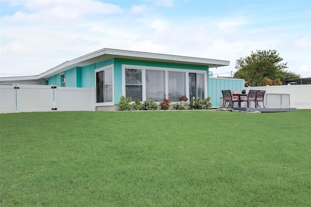 rear view of house featuring a yard and fence