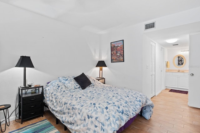 bedroom with hardwood / wood-style flooring, connected bathroom, and a closet