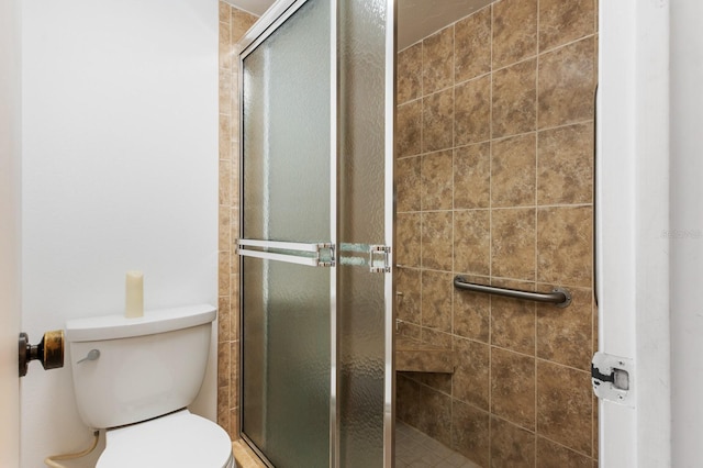 bathroom featuring a shower with shower door and toilet