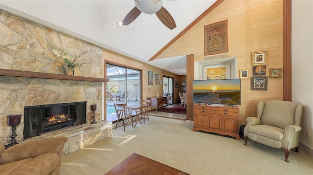 living area featuring light colored carpet, ceiling fan, a textured ceiling, a fireplace, and high vaulted ceiling