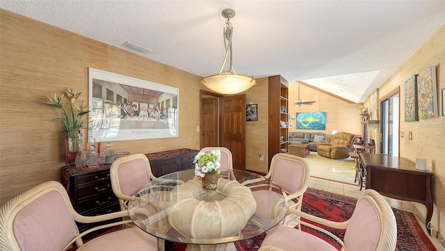 dining room featuring wallpapered walls, visible vents, vaulted ceiling, and a textured ceiling