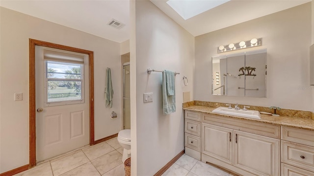 bathroom with a skylight, visible vents, toilet, tile patterned floors, and vanity