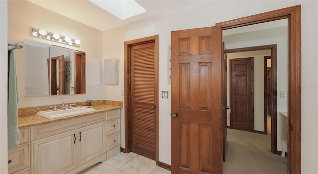 bathroom with a skylight, vanity, and baseboards