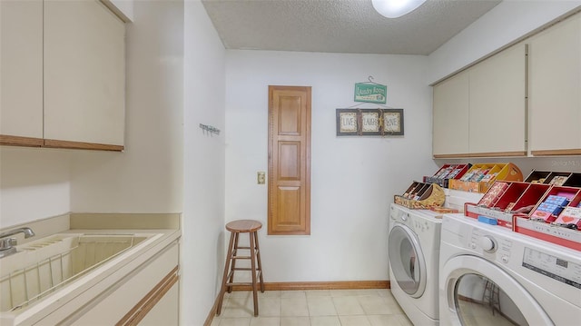 clothes washing area featuring cabinet space, baseboards, washing machine and clothes dryer, a textured ceiling, and a sink