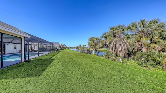 view of yard with a water view, glass enclosure, and an outdoor pool