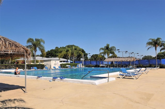 community pool with a patio area and fence