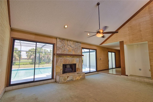3837 Torrey Pines Blvd, Sarasota, FL 34238 - unfurnished living room featuring carpet floors, a textured ceiling, a ceiling fan, healthy amount of natural light, and a stone fireplace