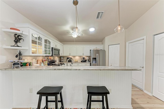 kitchen featuring appliances with stainless steel finishes, white cabinets, a kitchen breakfast bar, and kitchen peninsula