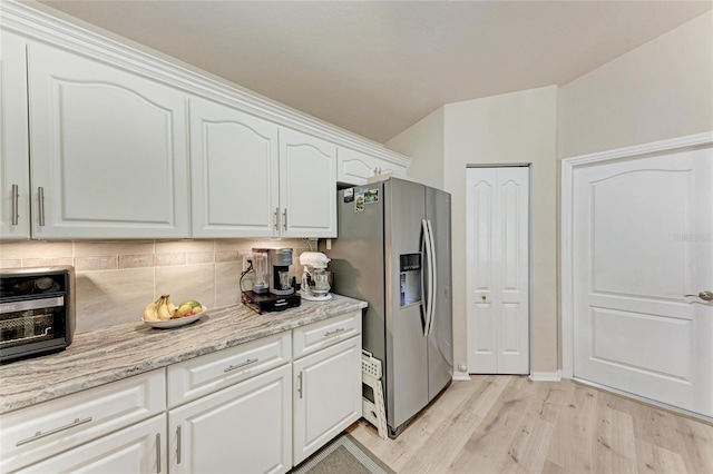 kitchen with stainless steel refrigerator with ice dispenser, white cabinetry, light hardwood / wood-style flooring, light stone countertops, and backsplash