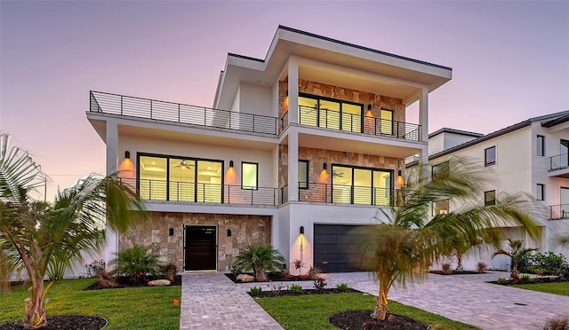 modern home featuring a garage, a yard, and a balcony