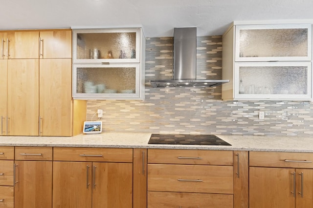 kitchen featuring tasteful backsplash, black electric stovetop, light stone countertops, and wall chimney range hood