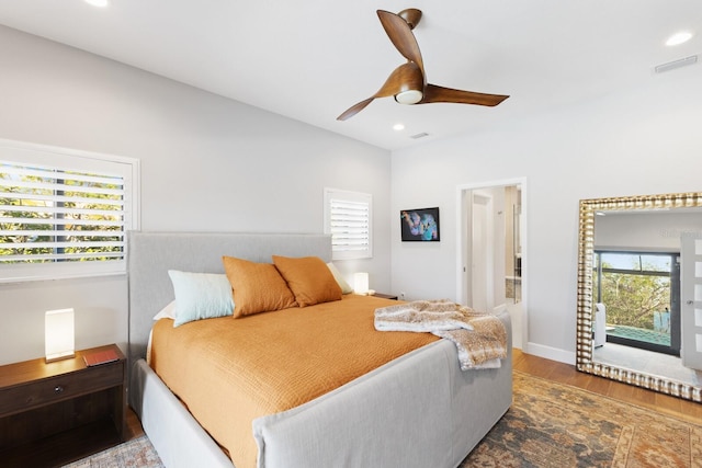 bedroom featuring multiple windows, wood-type flooring, and ceiling fan