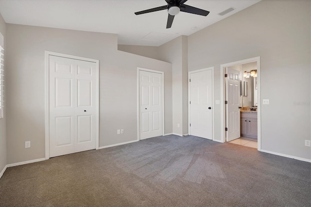 unfurnished bedroom featuring lofted ceiling, ceiling fan, multiple closets, light carpet, and ensuite bathroom